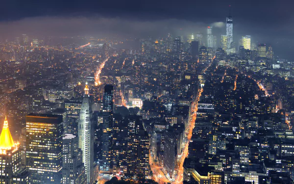 Aerial night view of Manhattan, New York skyline with glowing streets and skyscrapers — 4K Ultra HD PC desktop wallpaper/background highlighting man-made city lights.