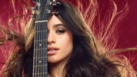 HD desktop wallpaper of a brunette Latina singer with brown eyes holding a guitar, featuring Camila Cabello against a vibrant red background.