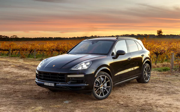 Black Porsche Cayenne SUV parked on a dirt road by vineyards at sunset — 4K Ultra HD PC desktop wallpaper and background.