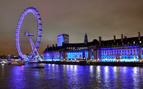 Night view of the illuminated London Eye and nearby buildings reflecting off the Thames River, creating a stunning HD desktop wallpaper and background.