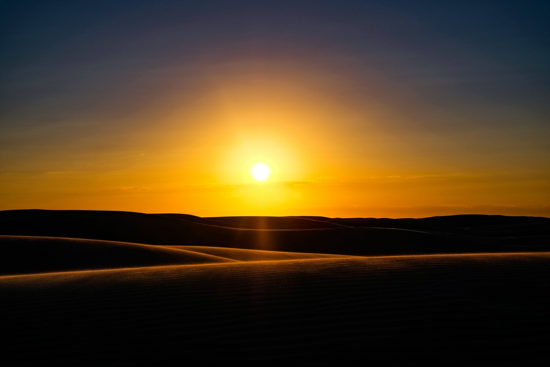 A vibrant 4K Ultra HD desert landscape featuring the sun setting behind sand dunes under a clear sky.