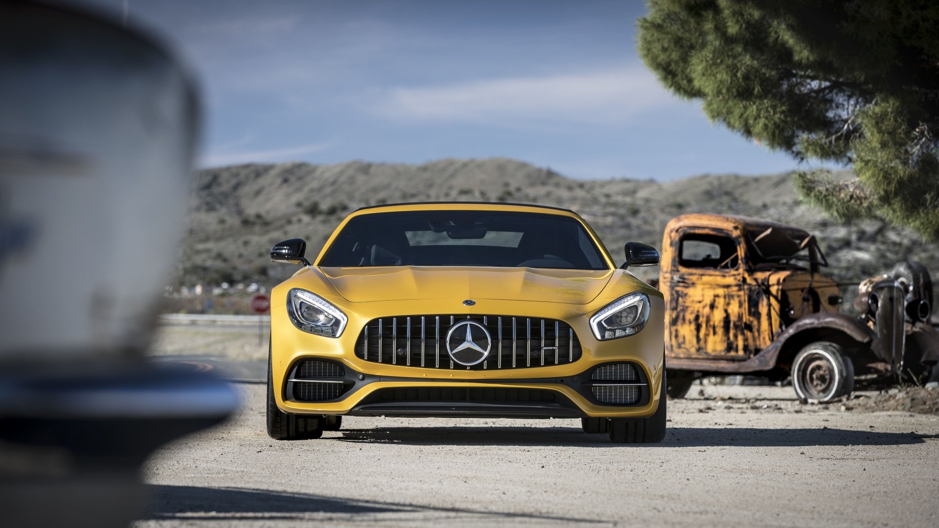 Yellow Mercedes-AMG GT R supercar front view parked in a dry landscape beside a rusted truck — 5K Ultra HD PC desktop wallpaper.