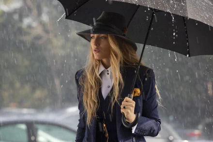 Woman in rain-drenched navy suit and wide-brim hat holding a black umbrella, cinematic still evoking the film A Simple Favor — 4K Ultra HD PC desktop wallpaper.