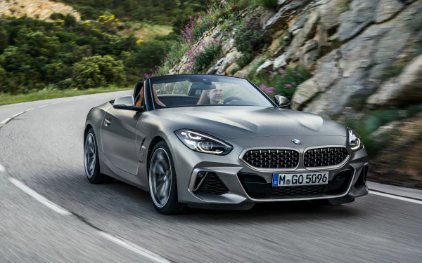 Silver BMW Z4 convertible sports car driving on a winding mountain road, captured in 4K Ultra HD as a desktop wallpaper and background.