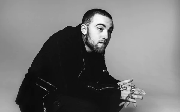 HD wallpaper featuring a monochrome portrait of a seated man, hands intertwined, against a plain background.