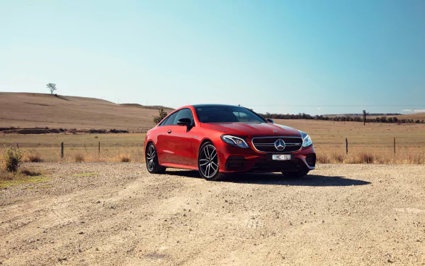 Red Mercedes-Benz E-Class coupe parked on a gravel road in open countryside, 4K Ultra HD PC desktop wallpaper of a Mercedes-Benz car/vehicle.