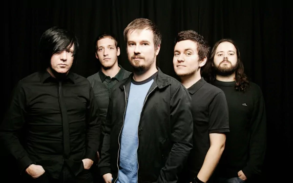 A group of five musicians from the band Funeral for a Friend poses confidently against a dark backdrop, showcasing their distinct styles in this HD desktop wallpaper.