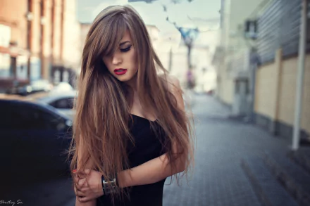 HD PC desktop wallpaper and background of a brunette woman model with long, flowing hair and red lipstick on a blurred urban street; shallow depth of field.