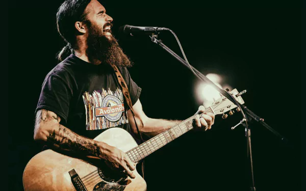 Cody Jinks passionately performs on stage, guitar in hand, capturing the essence of live music in this vibrant HD wallpaper and background.