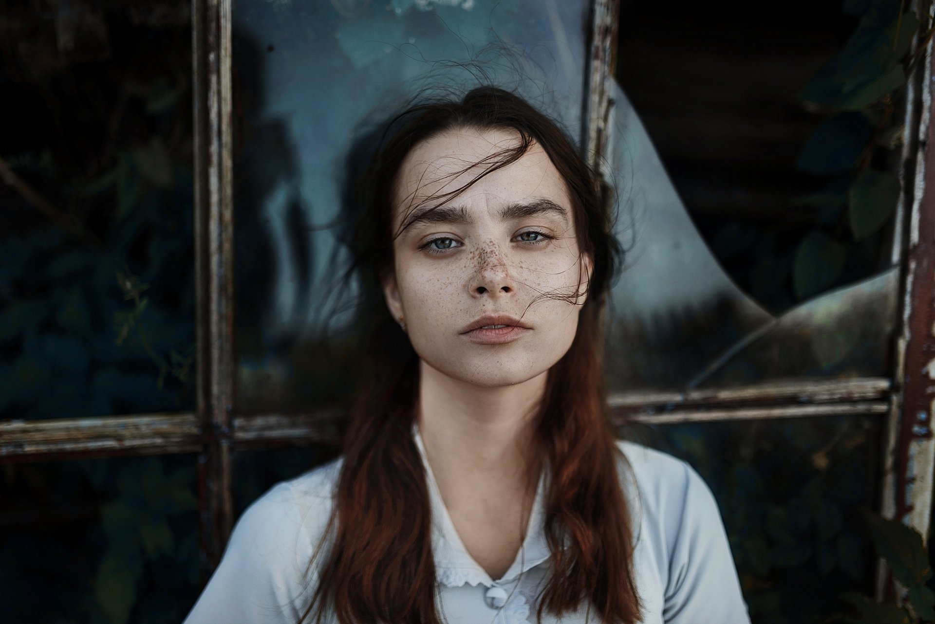 HD desktop wallpaper of a redhead model: freckled woman with long hair and blue eyes in front of a weathered window.