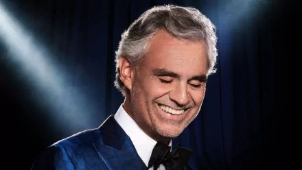 HD desktop wallpaper of a smiling man in a blue velvet tuxedo against a blue stage curtain backdrop.