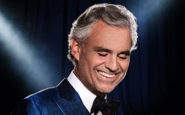 HD desktop wallpaper of a smiling man in a blue velvet tuxedo against a blue stage curtain backdrop.