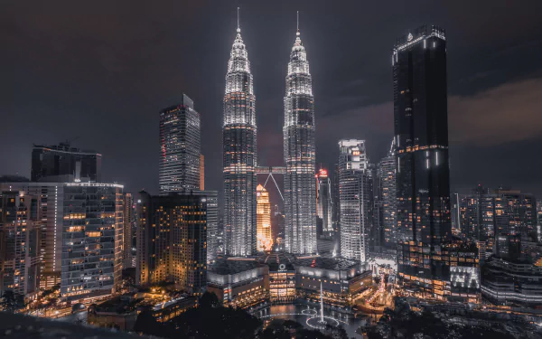 Night view of Kuala Lumpur's illuminated Petronas Towers and surrounding cityscape captured in 4K Ultra HD for a stunning PC desktop wallpaper.