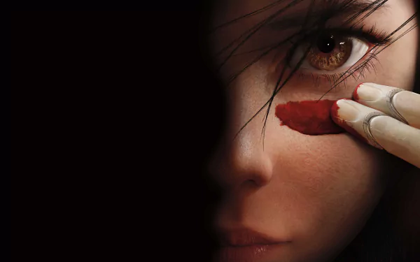 Close-up HD wallpaper of Alita from the movie Alita: Battle Angel, featuring her intense eye and a finger applying red paint beneath it.