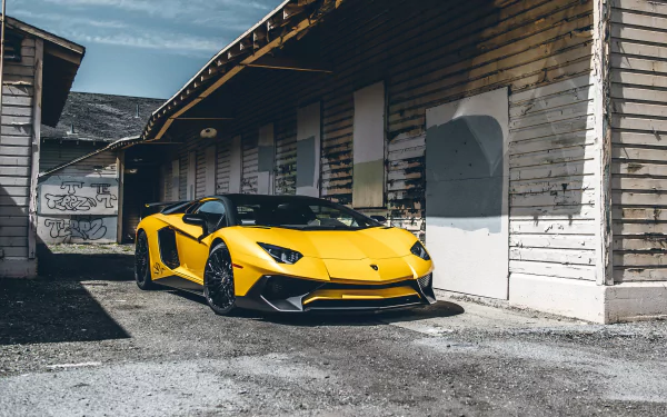 Yellow Lamborghini Aventador SV supercar parked beside weathered wooden buildings under a cloudy sky, captured in stunning 4K Ultra HD detail.