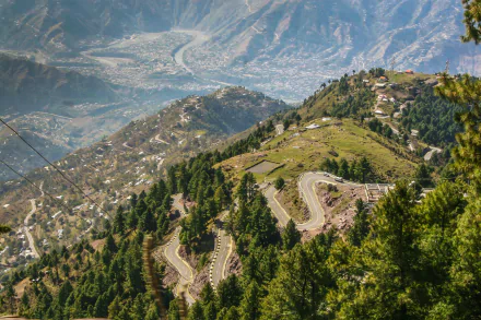 Scenic HD wallpaper of a winding road through lush green mountains in Kashmir, Pakistan, showcasing stunning nature and panoramic mountain photography.