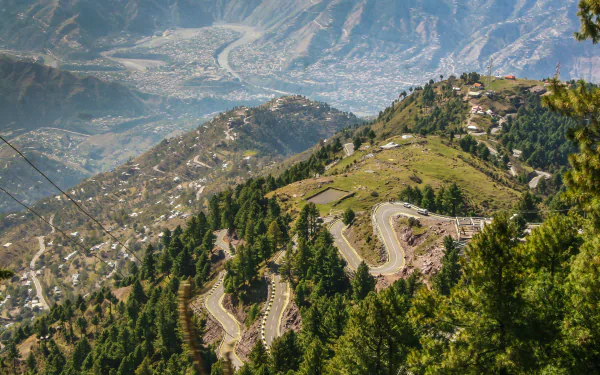 Scenic HD wallpaper of a winding road through lush green mountains in Kashmir, Pakistan, showcasing stunning nature and panoramic mountain photography.