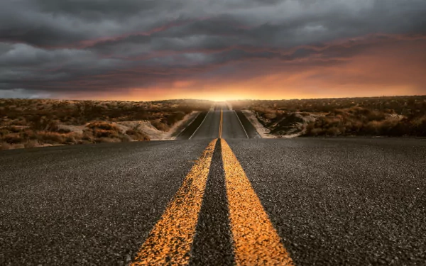 A man-made road stretches through a rugged landscape under dramatic clouds, captured in HD for a vivid desktop wallpaper and background.
