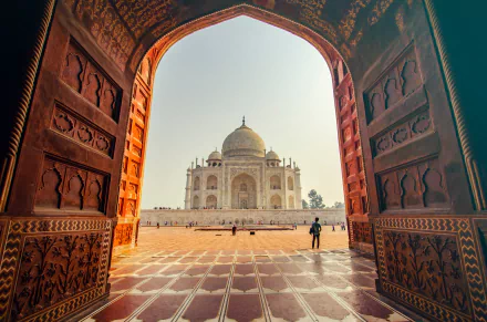A stunning 4K Ultra HD view of the Taj Mahal framed by an ornate archway, showcasing India's iconic man-made architectural masterpiece.