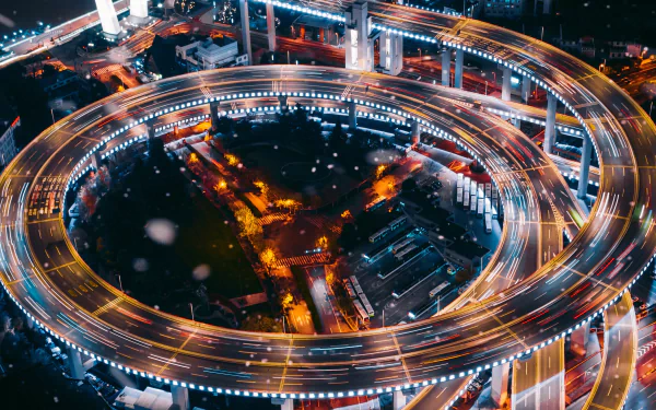 Nanpu Bridge, Shanghai, China — night aerial of spiral man-made highway with time-lapse light trails; 2K Quad HD PC desktop wallpaper/background.