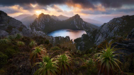 HD desktop wallpaper of Lake Oberon in Tasmania, showcasing a serene mountain landscape with lush vegetation and a dramatic sky at sunrise or sunset.