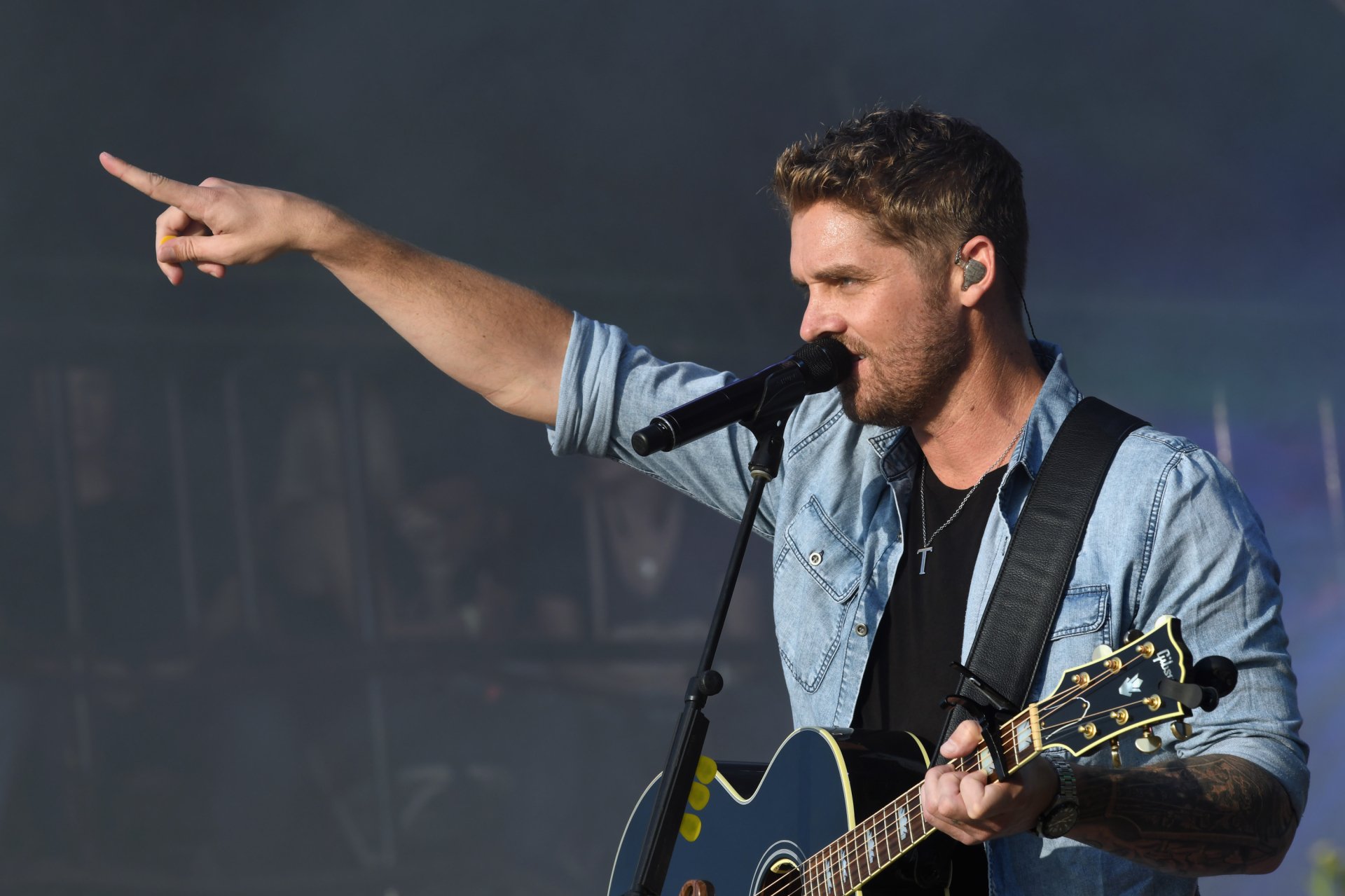 HD desktop wallpaper of a musician on stage with a guitar, pointing into the distance during a performance.