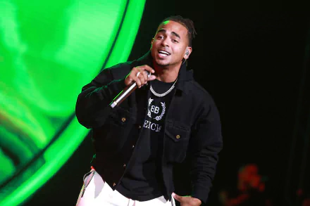 HD wallpaper of the artist performing on stage, microphone in hand, against a vibrant green background.