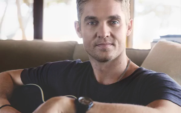 HD desktop wallpaper featuring a person holding a guitar, posing confidently for a relaxed, casual portrait.