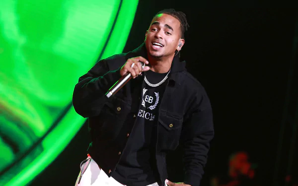 HD wallpaper of the artist performing on stage, microphone in hand, against a vibrant green background.