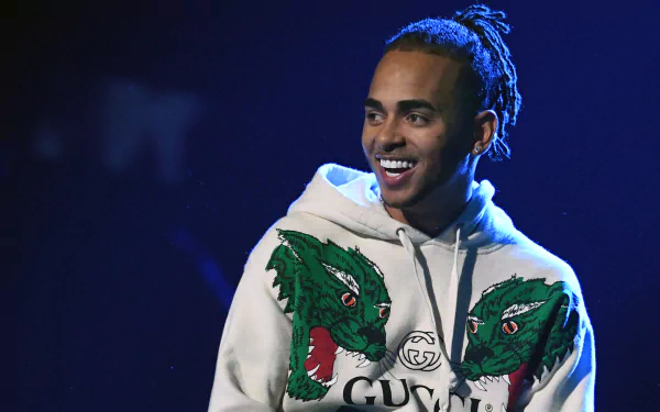 HD wallpaper of a smiling man in a hoodie with a dragon design, tagged as Ozuna, suitable as a desktop background.